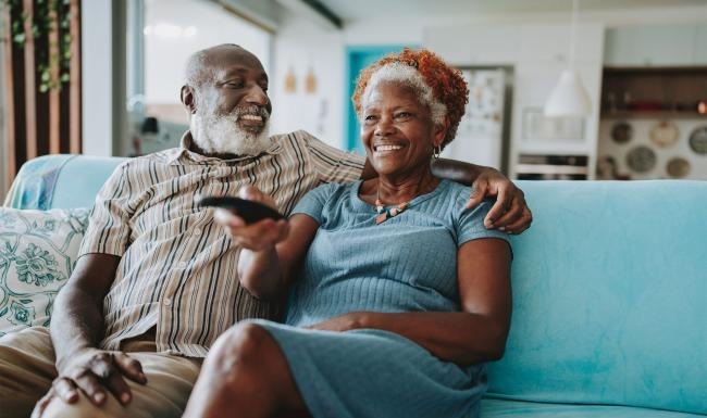 a man and woman sitting on a couch watching TV